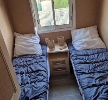 Intérieur du mobilhome avec deux lits simples et fenêtre dans le Mobilhome spacieux