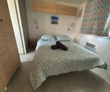Chambre intérieure avec lit double et serviettes pliées dans le mobilhome sur camping 4 étoiles