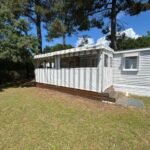 Extérieur d'un mobilhome sur pelouse sous les pins au Mobilhome sur camping 4 étoiles