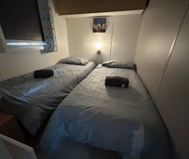 Chambre avec deux lits et serviettes pliées dans le Mobilhome sur camping 4 étoiles