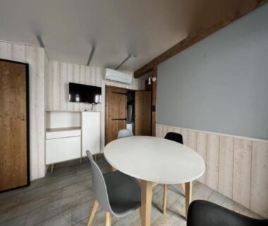 Salon intérieur avec table ronde, chaises et télévision dans le mobilhome tout confort