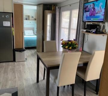 Intérieur avec coin repas cuisine télévision et chambre du Mobilhome tout confort 40 m2 pour 4 personnes