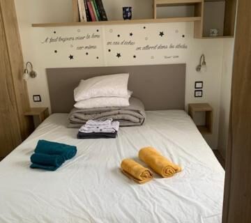 Chambre avec lit double serviettes pliées et rangements dans le Mobilhome tout confort 40 m2 pour 4 personnes