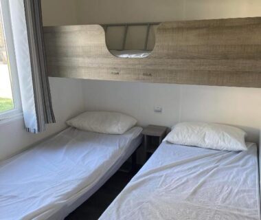 Chambre intérieure avec deux lits simples et lit superposé dans le mobilhome Sandra