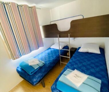 Chambre avec deux lits simples et lit en hauteur dans le mobilhome Mobilhomes de Pierrot