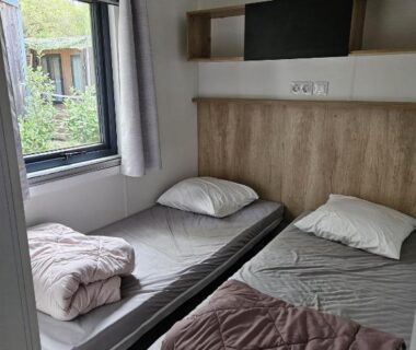 Chambre avec deux lits simples et fenêtre donnant sur jardin dans le Mobilhomme Privilège