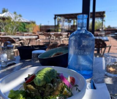 Terrasse ensoleillée avec salade et bouteille d'eau sur table au camping Mon Ptit coin au ferret