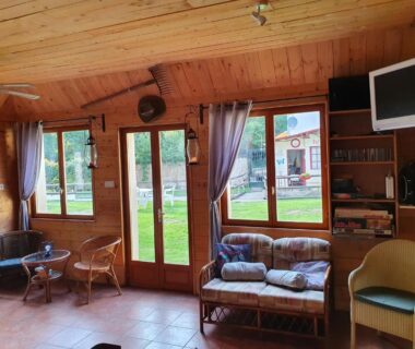 Salon en bois avec canapés et chaises dans le Moulin Du Pommier Glamping & Camping