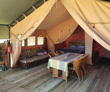 Intérieur de tente avec coin repas et salon au Moulin Du Pommier Glamping et Camping