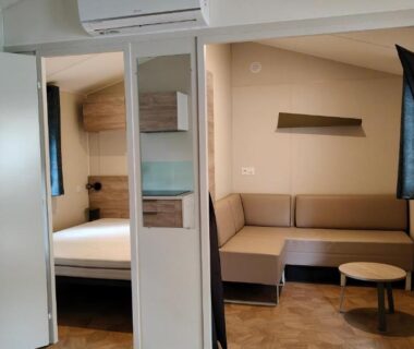 Intérieur du mobil-home avec salon canapé et chambre attenante au NATITOLOCATION Mobile Home Camping 4etoiles Saint Cyprien