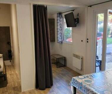 Intérieur du mobile home avec table et porte-fenêtre donnant sur terrasse dans le NATITOLOCATION Mobile Home Saint Cyprien