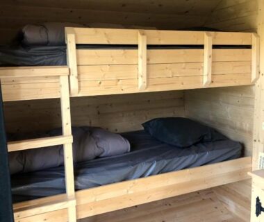 Intérieur en bois avec lits superposés au Camping Armor Loisirs