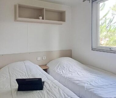 Chambre avec deux lits et fenêtre dans le mobil-home Naphtase MH01S Le Refuge des Pins