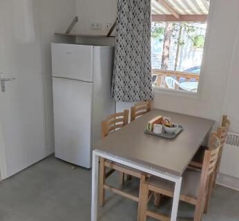 Intérieur coin repas avec frigo et table dans le mobil-home Naphtase MH487S Pause Privilège