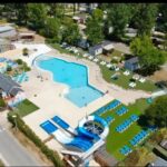 Piscine extérieure avec toboggan et chaises longues au camping Nat & Mayou