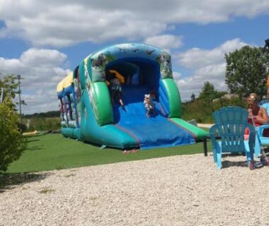 Aire de jeux aquatique avec toboggan gonflable sur pelouse au camping Nat & Mayou