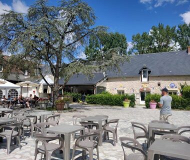 Cour pavée avec tables et parasols dans le camping Nat & Mayou