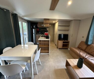 Intérieur mobil home avec salon canapé et cuisine du Natuara L'écrin du Ferret