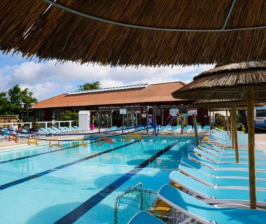 Piscine extérieure avec couloirs de nage et transats au camping Natuara L'horizon du lac