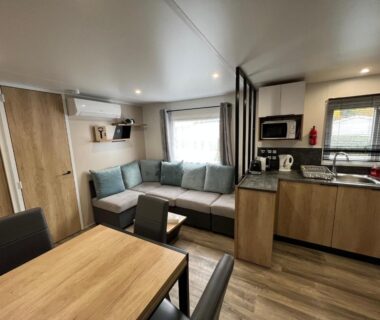 Intérieur du mobil-home avec coin salon et cuisine du Natuara L'horizon du lac Wifi inclu