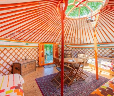 Intérieur de yourte avec lits, table et puits de lumière au Natura Lodge