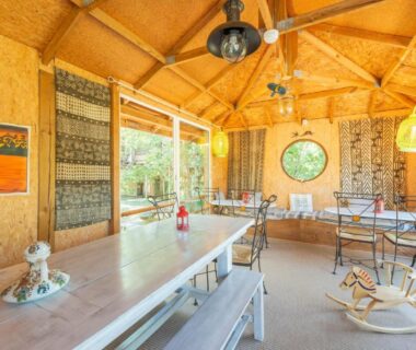 Salle à manger intérieure avec longue table et bancs dans le Natura Lodge