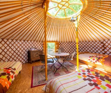Intérieur de yourte avec lits et table au Natura Lodge