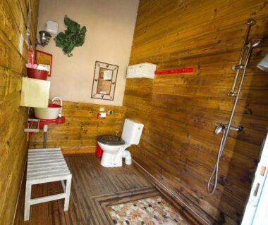 Salle de bain en bois avec douche et toilettes dans le Natura Lodge