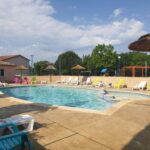 Piscine extérieure avec transats parasols et aire de jeux au camping Oasis des Garrigues