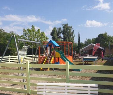 Aire de jeux avec toboggan balançoires et clôture au camping Oasis des Garrigues