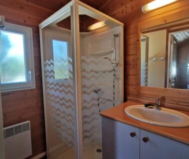 Salle de bain en bois avec douche et lavabo du camping Oasis des Garrigues