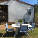 Espace repas extérieur avec table et chaises devant un mobil-home à l'Oasis village