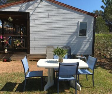 Espace repas extérieur avec table et chaises devant un mobil-home à l'Oasis village