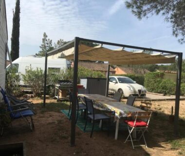 Espace extérieur sous pergola avec table et chaises à Oasis village