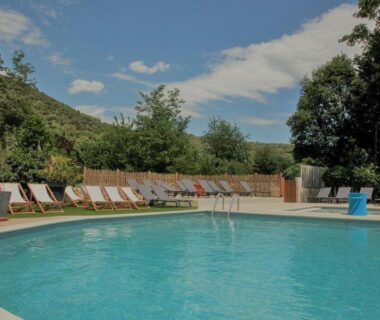 Piscine extérieure entourée de transats dans un cadre boisé au Medrose Camping Ardèche