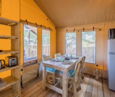 Intérieur de tente avec table chaises et réfrigérateur au Medrose Camping Ardèche