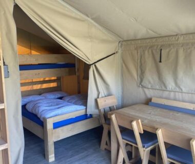 Intérieur de tente lodge avec lits superposés et table à manger au Medrose Camping Ardèche