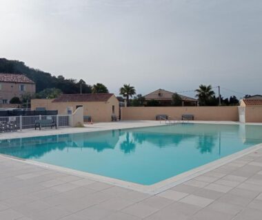 Piscine extérieure et terrasse avec palmiers à Ohana Cottage