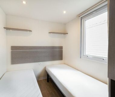 Chambre avec deux lits simples et fenêtre dans l'Ohana Cottage