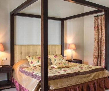 Chambre avec lit à baldaquin et portes-fenêtres donnant sur jardin dans l'OliviersMaison H1