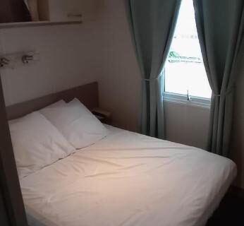 Chambre intérieure avec lit double et rideaux dans l'hébergement Omaha beach mobilhome