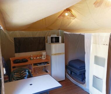 Intérieur de tente aménagée avec kitchenette et table à manger au Paradis Des Dombes