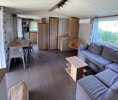 Intérieur avec salon canapé et kitchenette dans le bungalow du Parc Résidentiel La Listra