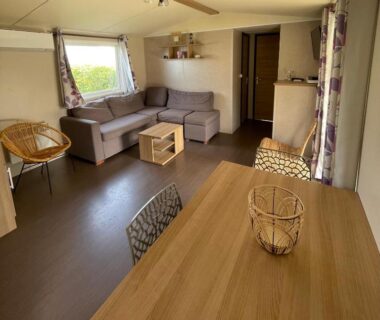 Salon avec canapé et table à manger dans le bungalow du Parc Résidentiel La Listra