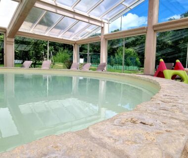 Piscine couverte avec transats dans la véranda du Parc de Nibelle