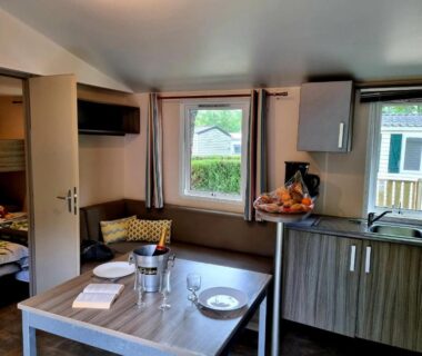Intérieur de mobil-home avec table, banquette et kitchenette au Parc de Nibelle