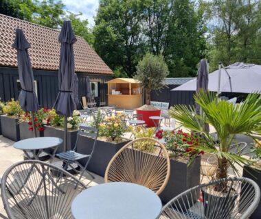 Terrasse avec tables chaises et parasols au Parc de Nibelle