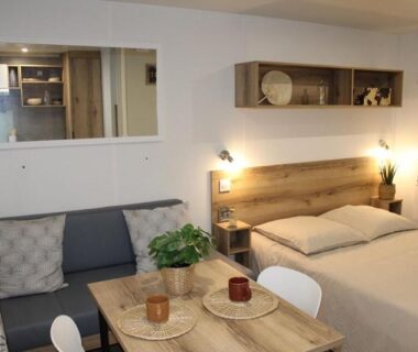Intérieur avec lit double et coin repas dans le mobil-home Parc de Nibelle