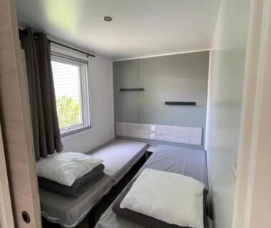 Chambre avec deux lits simples et fenêtre sur verdure dans le camping Parenthèse nature au Cap Ferret