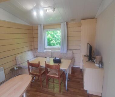 Salon avec coin repas et télévision donnant sur la verdure dans le mobilhome 2 chambres 5 personnes Paris Eure gestion